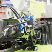 Plastic injection molding machine with automatic material feeding system at B-Pen Plastic manufacturing facility