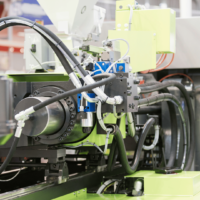 Plastic injection molding machine with automatic material feeding system at B-Pen Plastic manufacturing facility