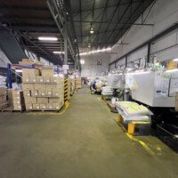 Packed goods and raw material beside active injection molding machines at B-Pen Plastic factory